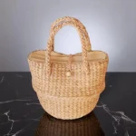 Among vegan raffia straw bag with braided handles and button closure.