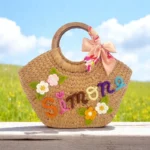Handwoven personalised straw tote bag with colourful floral embroidery and custom name detail, eco-friendly and handmade in Thailand.