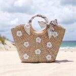 Floral straw beach tote with white daisy embroidery, circular handles wrapped in ivory bows