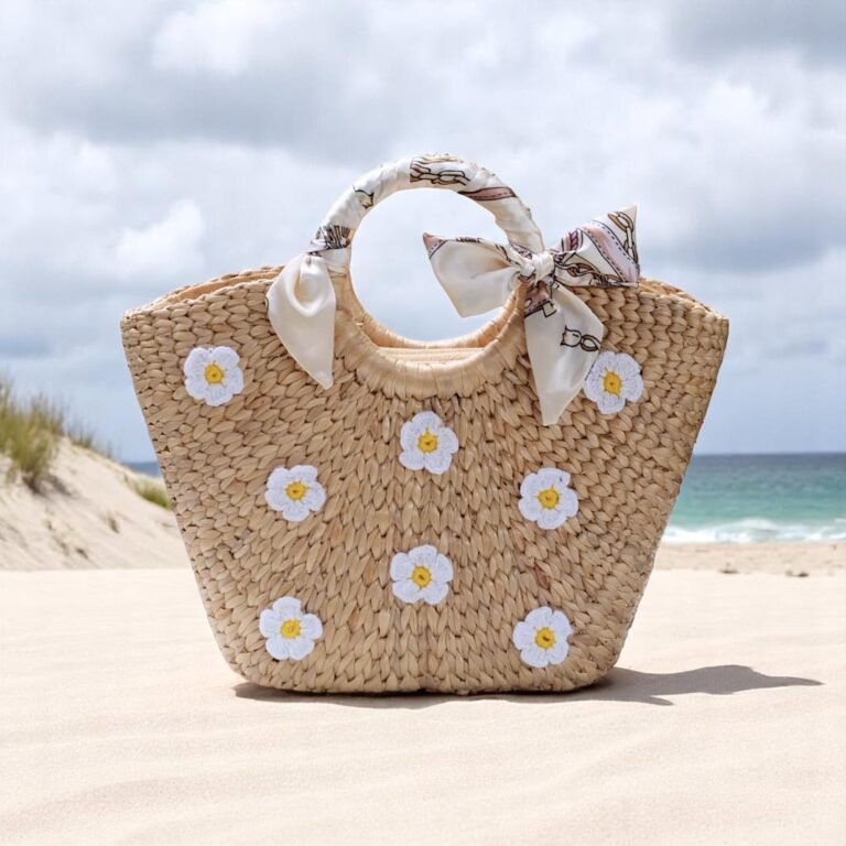 Floral straw beach tote with white daisy embroidery, circular handles wrapped in ivory bows